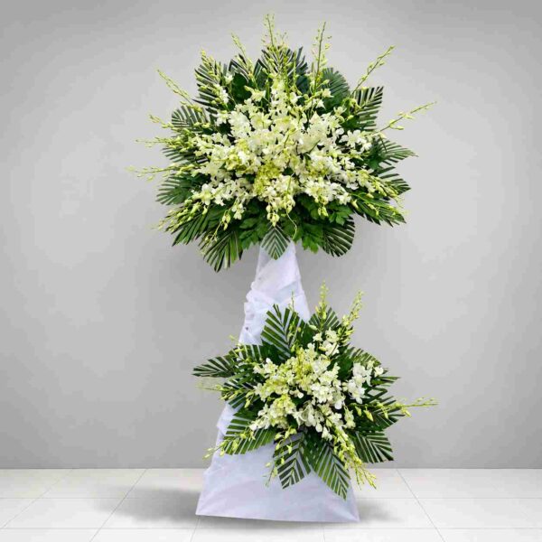 Kệ Hoa Viếng Thiên Thu 557 với tông trắng trang nhã, thiết kế hai tầng sang trọng kết hợp hoa lan trắng và lá xanh, thể hiện sự tiếc thương và thành kính.