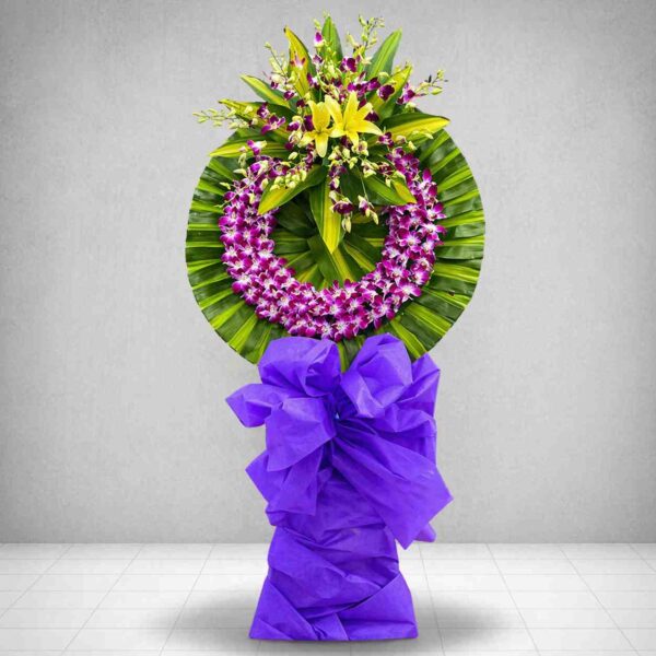 Kệ hoa chia buồn Giã Từ với vòng lan tím sang trọng, hoa ly vàng nổi bật và nơ tím trang nghiêm