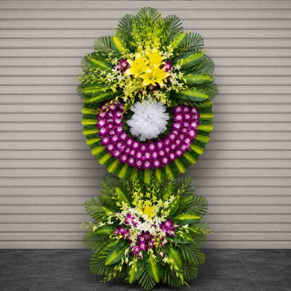 Kệ hoa chia buồn 040 nổi bật với vòng hoa lan tím kết hợp hoa ly vàng và lá xanh sang trọng, thiết kế hiện đại hai tầng.