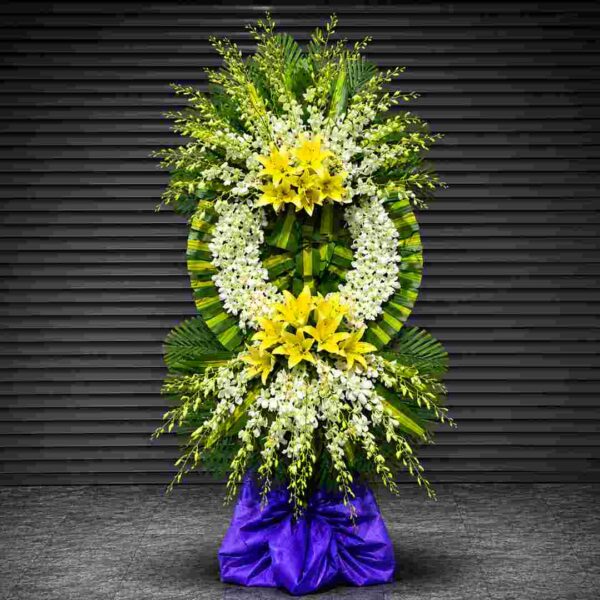 Kệ hoa chia buồn 035 với vòng hoa lan trắng kết hợp hoa ly vàng nổi bật, thiết kế hai tầng sang trọng trên nền lá xanh nghệ thuật, thể hiện sự tiếc thương và lòng thành kính sâu sắc.