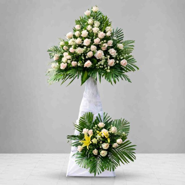 Kệ hoa chia buồn 012 tông trắng kem sang trọng với hoa hồng, hoa ly và lá xanh trang nhã gửi lời tiễn biệt chân thành