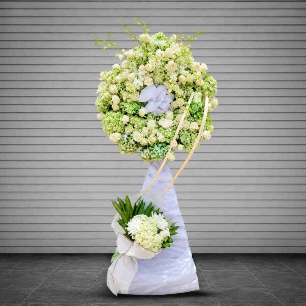 Kệ hoa thương tiếc 02 tông trắng xanh sang trọng với hoa hồng trắng, cẩm tú cầu xanh nhạt và hoa lan trắng, thiết kế trang nghiêm gửi lời chia buồn sâu sắc.