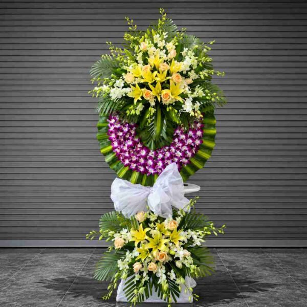 Kệ hoa chia buồn 125 thiết kế hai tầng sang trọng với hoa ly vàng, hoa hồng kem, lan tím và lá xanh nổi bật, thể hiện sự tiếc thương chân thành.