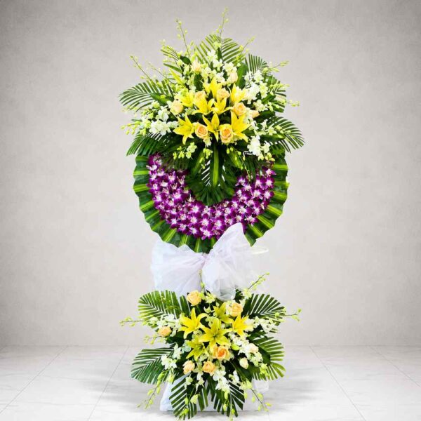 Kệ hoa chia buồn 125 thiết kế hai tầng sang trọng với hoa ly vàng, hoa hồng kem, lan tím và lá xanh nổi bật, thể hiện sự tiếc thương chân thành.