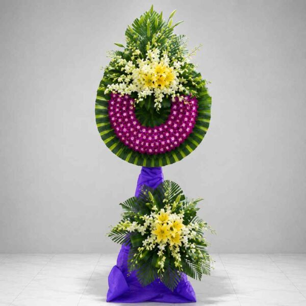 Kệ hoa chia buồn 132 với vòng hoa lan tím nổi bật kết hợp hoa ly vàng và hoa trắng, thiết kế trang trọng thể hiện sự tiếc thương sâu sắc.