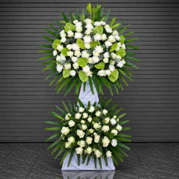 Kệ hoa chia buồn 151 với hoa hồng trắng, cúc trắng và môn xanh, thiết kế hai tầng sang trọng, thể hiện lòng thành kính và sự tiếc thương sâu sắc