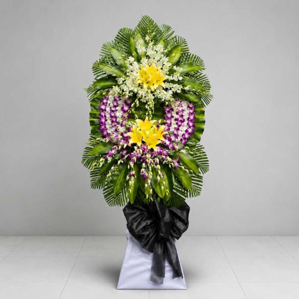 Kệ hoa chia buồn 117 nổi bật với hoa lan tím trắng, hoa ly vàng và lá xanh sang trọng, thiết kế hiện đại thể hiện sự kính trọng và tiếc thương sâu sắc.