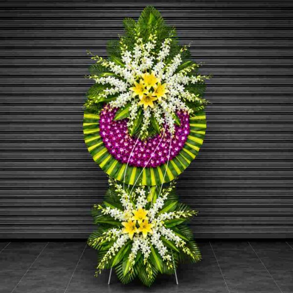 Kệ hoa chia buồn 127 nổi bật với hoa lan tím, hoa ly vàng và hoa trắng kết hợp cùng lá xanh nghệ thuật, thiết kế sang trọng thể hiện lòng tiếc thương sâu sắc.