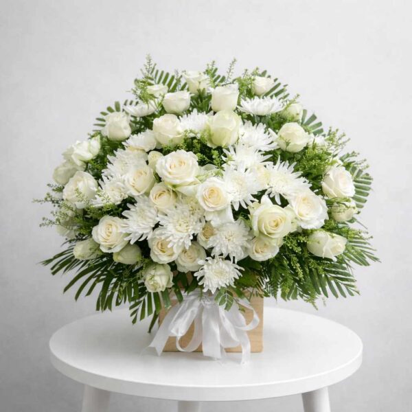 Giỏ hoa viếng trắng sang trọng với hoa hồng và hoa cúc tươi, thiết kế trang nhã đặt trên bàn trắng