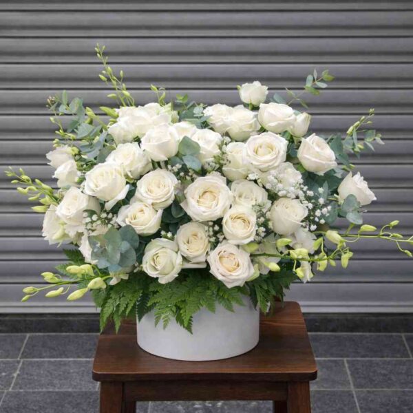 Giỏ hoa viếng chia buồn màu trắng trang nhã với hoa hồng trắng, hoa baby và lá xanh sang trọng