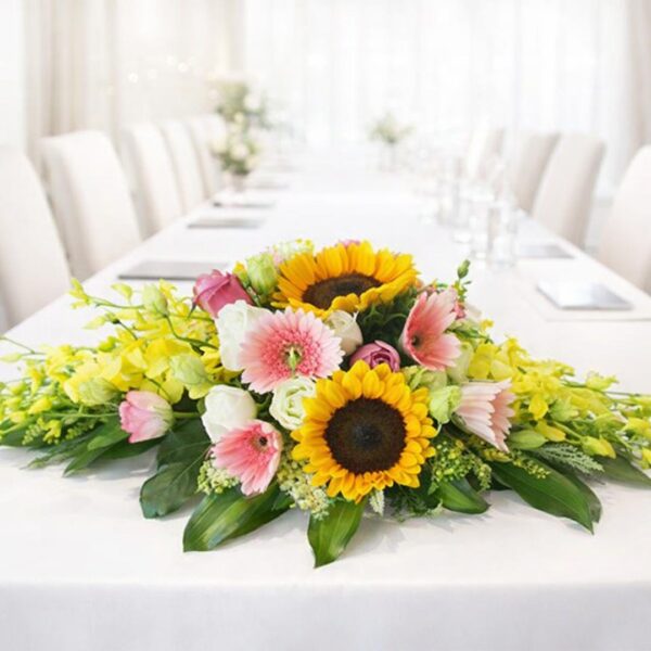 Hoa để bàn hội nghị tông vàng hồng với hoa hướng dương và đồng tiền nổi bật