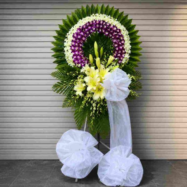 Kệ Hoa Chia Buồn Thương Nhớ 116 với vòng hoa lan tím trắng sang trọng, điểm nhấn hoa ly trắng và nơ trắng trang nhã thể hiện sự tiếc thương sâu sắc.