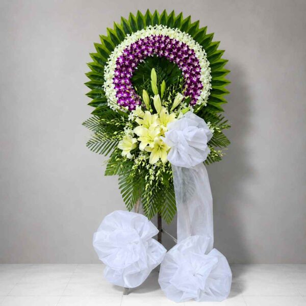 Kệ Hoa Chia Buồn Thương Nhớ 116 với vòng hoa lan tím trắng sang trọng, điểm nhấn hoa ly trắng và nơ trắng trang nhã thể hiện sự tiếc thương sâu sắc.