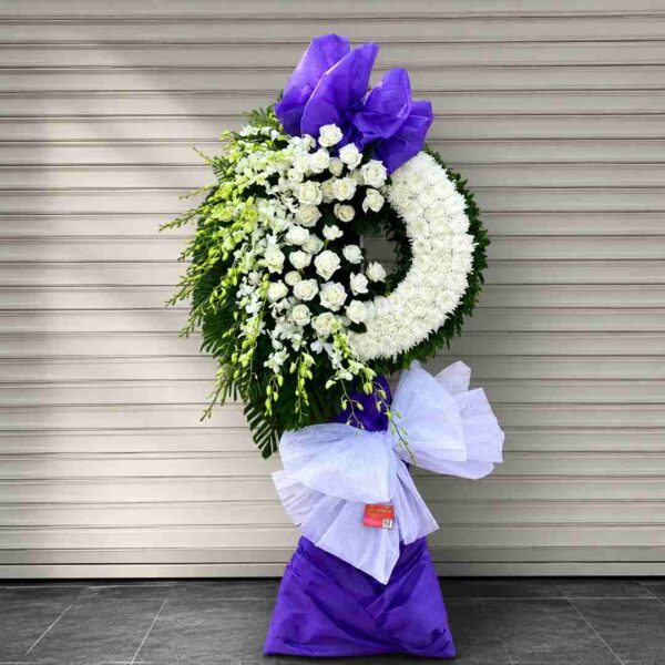 Kệ hoa chia buồn 198 tông trắng tím sang trọng với vòng hoa viếng thiết kế hiện đại, hoa trắng kết hợp nơ tím nổi bật gửi lời tiễn biệt trang trọng.