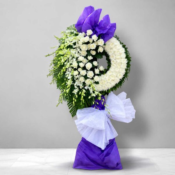 Kệ hoa chia buồn 198 tông trắng tím sang trọng với vòng hoa viếng thiết kế hiện đại, hoa trắng kết hợp nơ tím nổi bật gửi lời tiễn biệt trang trọng.