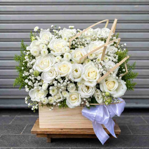 Giỏ hoa chia buồn với hoa hồng trắng, hoa baby trắng và lá xanh được cắm trong hộp gỗ sang trọng