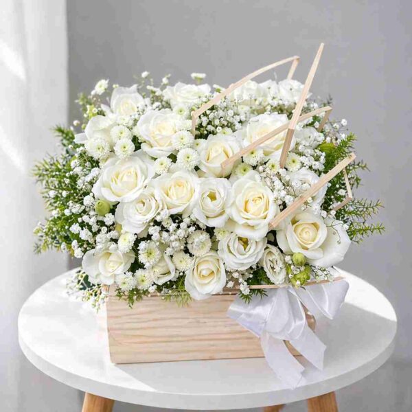 Giỏ hoa chia buồn với hoa hồng trắng, hoa baby trắng và lá xanh được cắm trong hộp gỗ sang trọng