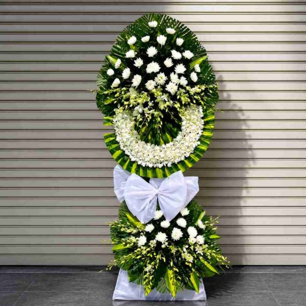 Kệ hoa chia buồn 315 với tông hoa trắng trang nhã kết hợp lá xanh, thiết kế 2 tầng sang trọng phù hợp gửi viếng tang lễ.