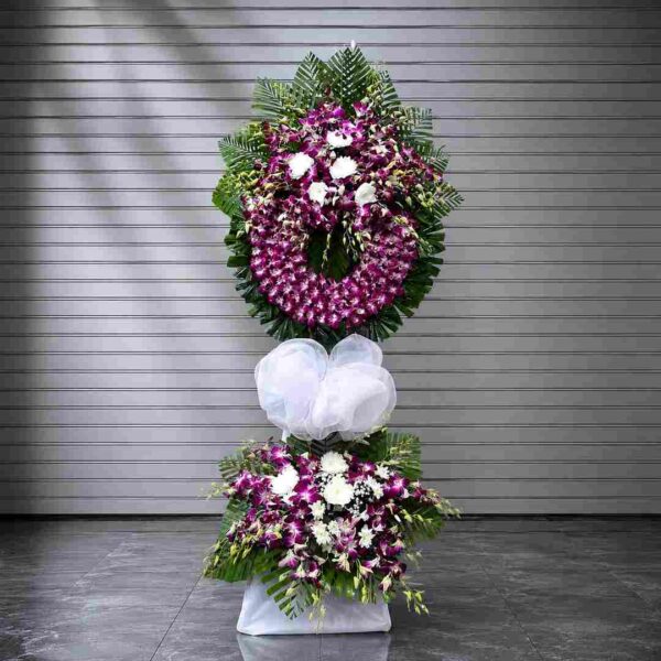 Kệ hoa chia buồn 320 thiết kế vòng hoa lan tím nổi bật kết hợp hoa trắng và lá xanh nghệ thuật, mang vẻ đẹp sang trọng và trang nghiêm.