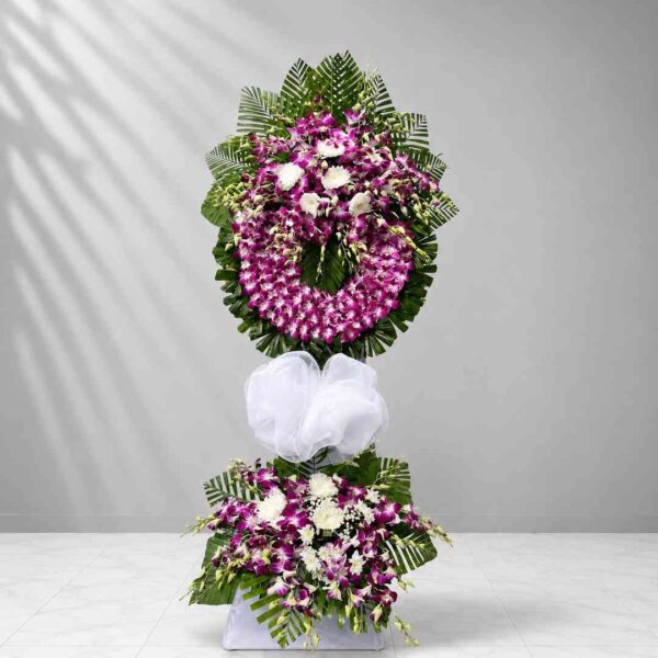 Kệ hoa chia buồn 320 thiết kế vòng hoa lan tím nổi bật kết hợp hoa trắng và lá xanh nghệ thuật, mang vẻ đẹp sang trọng và trang nghiêm.