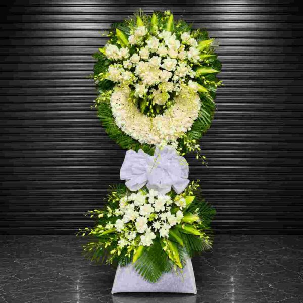 Kệ hoa chia buồn 330 với thiết kế vòng hoa trắng hai tầng sang trọng, kết hợp hoa hồng trắng, hoa cúc trắng, lan trắng và lá xanh cao cấp, thể hiện lòng thành kính và sự tiếc thương sâu sắc.