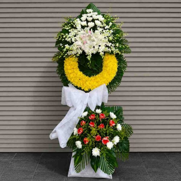 Kệ hoa chia buồn 334 thiết kế hai tầng với vòng hoa vàng nổi bật kết hợp hoa ly trắng, hoa cúc trắng và điểm nhấn hoa đỏ sang trọng.