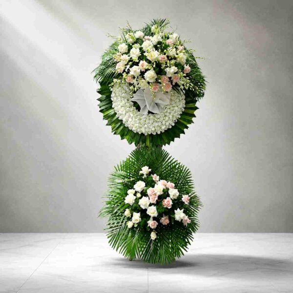 Kệ hoa chia buồn 336 tông trắng thanh lịch với vòng hoa trắng kết hợp hoa hồng trắng, hồng phấn và lá xanh sang trọng.