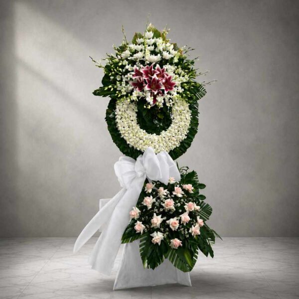 Kệ hoa chia buồn 340 với vòng hoa trắng sang trọng kết hợp hoa ly đỏ nổi bật, hoa hồng kem và lá xanh tinh tế.