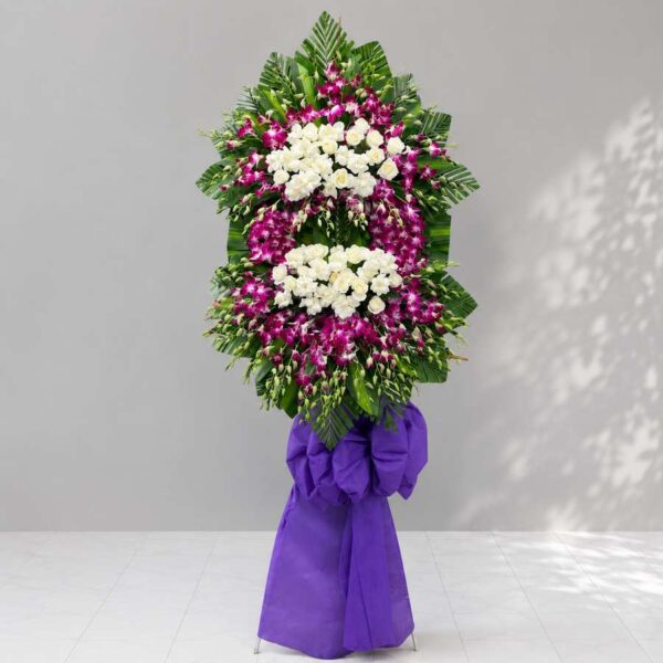 Kệ hoa chia buồn 356 với thiết kế hoa lan tím phối hoa hồng trắng sang trọng, nổi bật trên nền lá xanh tạo vẻ trang nghiêm và tinh tế.