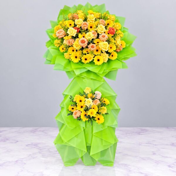 Kệ hoa chúc mừng Ánh Dương Thịnh Vượng với hoa hồng vàng, hoa đồng tiền vàng và giấy gói xanh