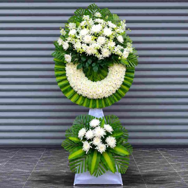 Kệ hoa chia buồn 328 tông trắng xanh sang trọng với vòng hoa cúc trắng kết hợp lá xanh nghệ thuật, thiết kế trang nghiêm và tinh tế