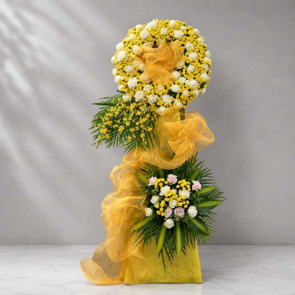Kệ hoa chia buồn 378 thiết kế hai tầng tông vàng trắng nổi bật, kết hợp hoa hồng trắng, hoa cúc vàng và nơ voan vàng sang trọng dành cho lễ viếng.