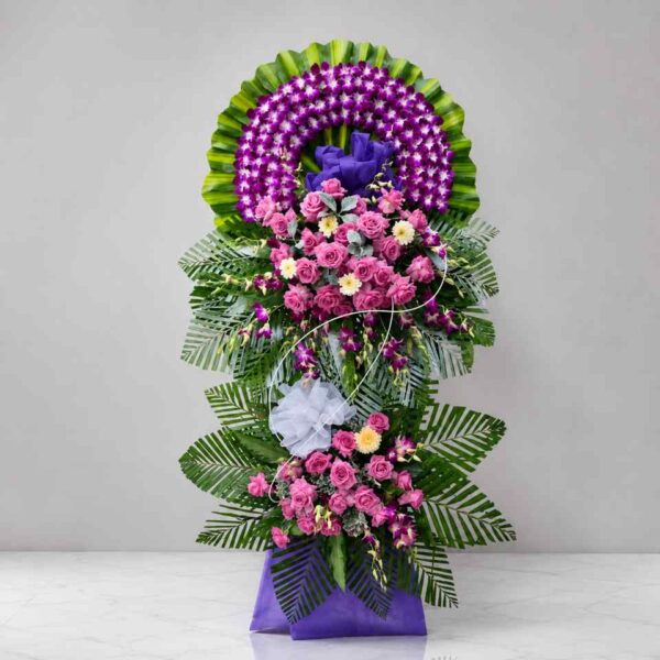 Shop hoa tươi Thanh Hóa- điện hoa Thanh Hóa uy tín 79 Kệ hoa chia buồn 389 thiết kế tông tím hồng nổi bật với hoa lan tím, hoa hồng hồng và lá xanh nghệ thuật, mang vẻ đẹp sang trọng và trang nghiêm.