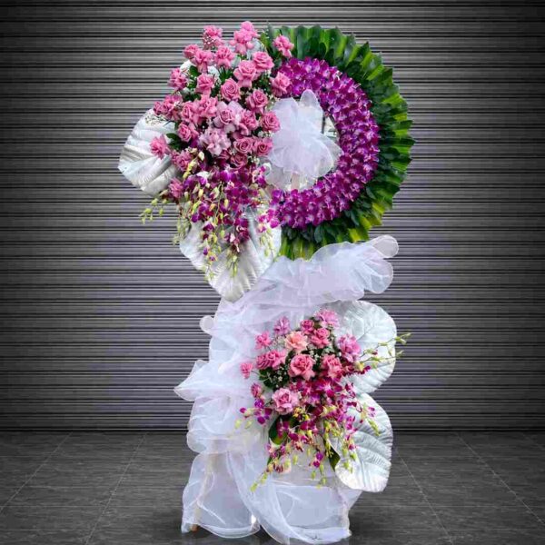 Kệ hoa chia buồn 399 với hoa hồng hồng, lan tím và vòng hoa nghệ thuật sang trọng nổi bật trên nền lá xanh hiện đại