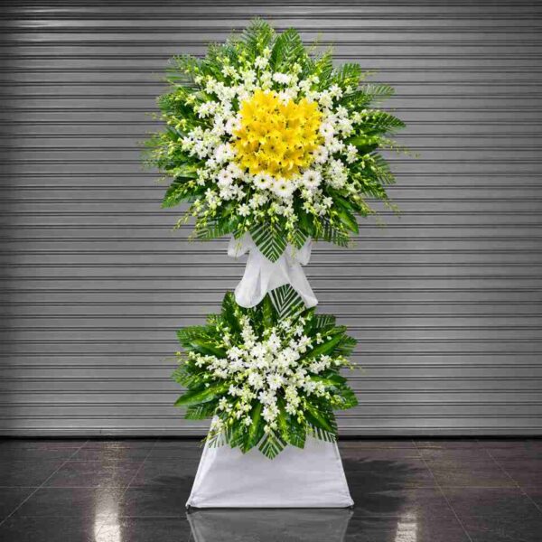 Kệ hoa chia buồn 412 với hoa ly vàng nổi bật kết hợp hoa trắng và lá xanh tươi, thiết kế hai tầng sang trọng thể hiện sự tiếc thương và chia sẻ sâu sắc.