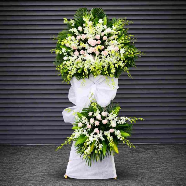 Kệ hoa chia buồn 381 với hoa lan trắng kết hợp hoa hồng phấn nhạt, thiết kế hai tầng sang trọng cùng lá xanh nghệ thuật, thể hiện sự tiếc thương và lòng thành kính sâu sắc.