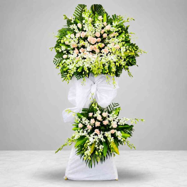 Kệ hoa chia buồn 381 với hoa lan trắng kết hợp hoa hồng phấn nhạt, thiết kế hai tầng sang trọng cùng lá xanh nghệ thuật, thể hiện sự tiếc thương và lòng thành kính sâu sắc.