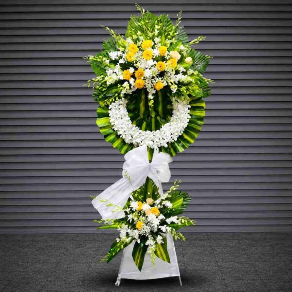 Kệ hoa chia buồn 410 với vòng hoa lan trắng kết hợp hoa vàng tươi, lá xanh nghệ thuật và nơ trắng trang nhã, thể hiện sự tiếc thương và lòng thành kính sâu sắc.