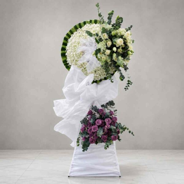 Kệ hoa chia buồn 415 với vòng hoa trắng trang nhã kết hợp hoa hồng kem, hoa hồng tím và lá xanh eucalyptus, thể hiện sự tiếc thương và lòng thành kính.