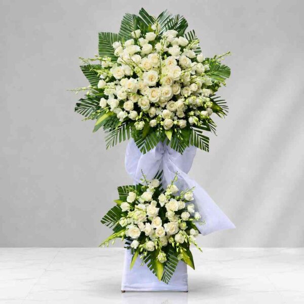 Kệ hoa chia buồn 424 với hoa hồng trắng cao cấp kết hợp lá xanh nghệ thuật, thiết kế hai tầng sang trọng thể hiện sự kính trọng và tiếc thương sâu sắc.