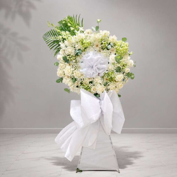 Kệ hoa chia buồn 446 thiết kế vòng hoa trắng sang trọng với hoa hồng trắng, cúc trắng và lá xanh tinh tế, thể hiện sự tiếc thương sâu sắc và trang nghiêm.