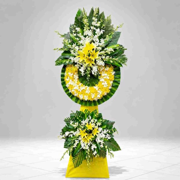 Kệ hoa chia buồn 514 với hoa ly vàng, lan trắng và vòng hoa vàng trắng trang trọng, thiết kế hai tầng sang trọng thể hiện sự tiếc thương và kính viếng sâu sắc.