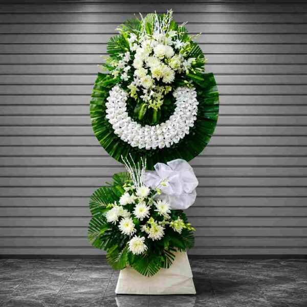 Kệ hoa chia buồn 529 tông trắng sang trọng với vòng hoa lan trắng kết hợp cúc trắng, lá xanh đậm, thiết kế trang nhã và trang nghiêm.