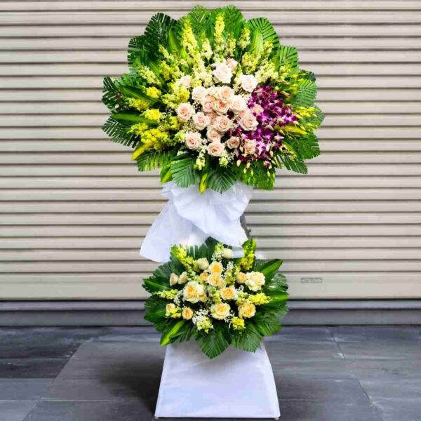 Lẵng Hoa Chia Buồn Lời Tiễn Cuối 496 với thiết kế 2 tầng sang trọng, kết hợp hoa hồng kem, lan tím, hoa trắng và lá xanh, gửi lời tiễn biệt đầy thành kính.