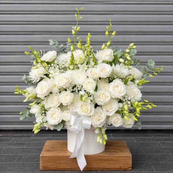 Giỏ hoa chia buồn 436 với hoa hồng trắng, cúc trắng và lá xanh được cắm trong hộp tròn thanh lịch