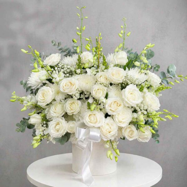 Giỏ hoa chia buồn 436 với hoa hồng trắng, cúc trắng và lá xanh được cắm trong hộp tròn thanh lịch