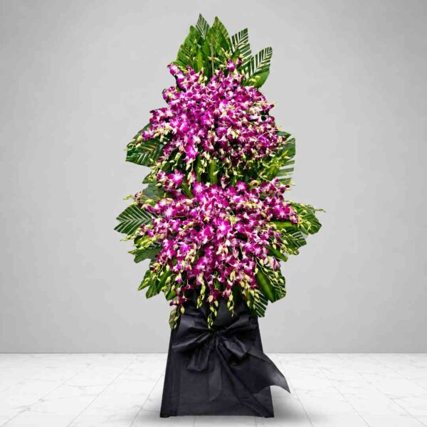 Kệ hoa chia buồn 509 nổi bật với sắc tím hồng của hoa lan dendro kết hợp lá xanh nhiệt đới, thiết kế hai tầng sang trọng thể hiện lòng thành kính và sự tiếc thương sâu sắc.