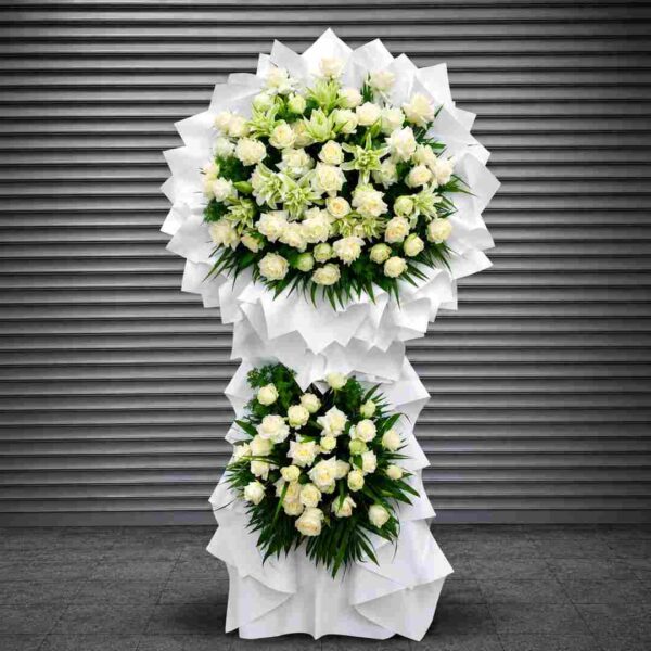Kệ hoa chia buồn 532 tông trắng trang nhã với hai tầng hoa hồng trắng và hoa ly trắng xanh, thiết kế sang trọng thể hiện lòng tiếc thương và sự kính trọng sâu sắc.