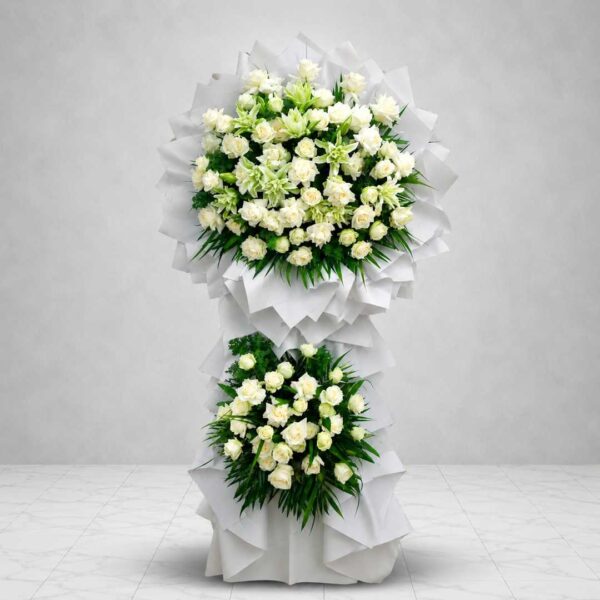Kệ hoa chia buồn 532 tông trắng trang nhã với hai tầng hoa hồng trắng và hoa ly trắng xanh, thiết kế sang trọng thể hiện lòng tiếc thương và sự kính trọng sâu sắc.
